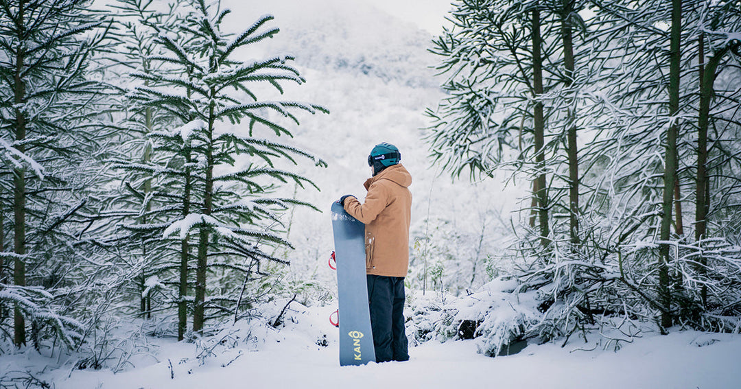 Hombre en la montaña con tabla de snowboard kano y equipamiento para nieve kano.